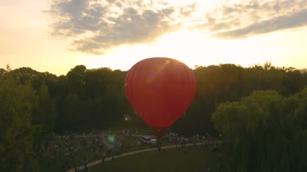 Menigte van mensen kijken naar de rode hete lucht ballon stijgt in zonovergoten hemel, festival — Stockvideo