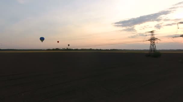 Ballons à air volant au-dessus des champs au crépuscule câbles électriques ci-dessous industrialisation — Video