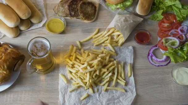 El hombre vertiendo papas fritas en salsa y beber cerveza, comer poco saludable, calorías — Vídeo de stock