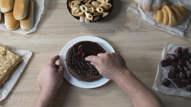 Accro à la nourriture coupant le gâteau en morceaux, mangeant du stress avec des bonbons, vue de dessus — Video