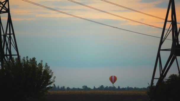 Lélegzetelállító kilátás nyílik a színes hőlégballon repül át a mező, a naplemente — Stock videók