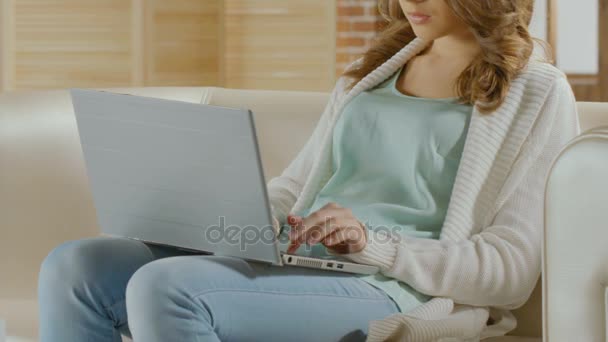 Freelancer sentada en el sofá y trabajando en el portátil, respondiendo al e-mail — Vídeos de Stock