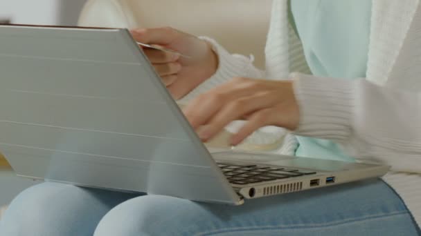 Женщина набирает номер карты на ноутбуке, покупает одежду онлайн, крупным планом — стоковое видео