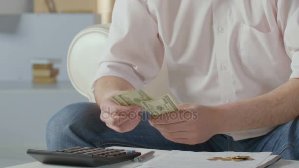 Mężczyzna liczy dolary, naciskając przyciski na Kalkulator, problemy finansowe kryzys — Wideo stockowe