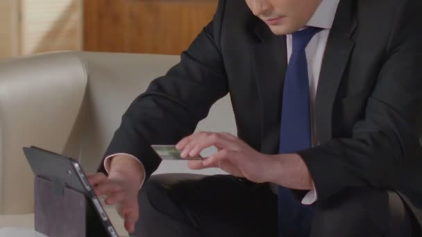 Hombre de traje de negocios escribiendo el número de tarjeta de crédito en la pantalla de la tableta, pagando facturas — Vídeo de stock