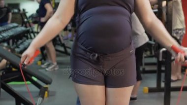 Obese woman training in the gym and jumping rope, fitness, weightloss workout