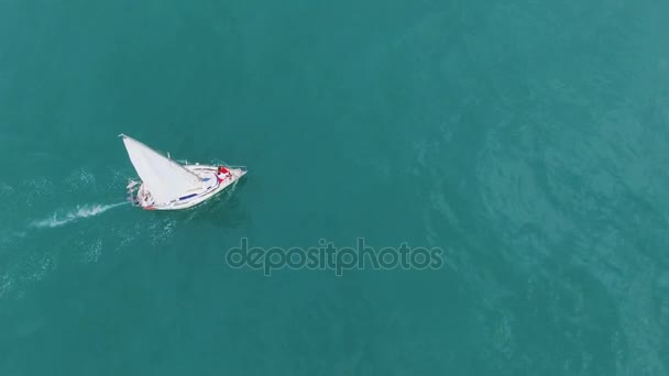 Чоловіча жінка стоїть на луці розкішного вітрильного човна, що проходить через бірюзове море — стокове відео