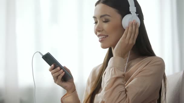 Привлекательная женщина слушает музыку в наушниках, любит радиостанцию, веселится — стоковое видео