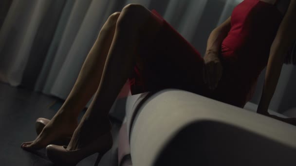 Chica femenina lentamente se quita zapatos magníficos en un sofá de dormitorio, pies desnudos — Vídeos de Stock