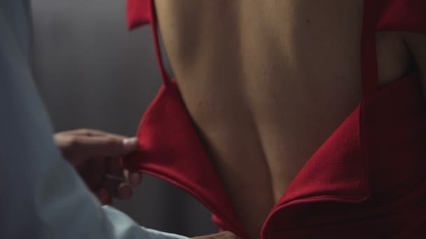 Τρυφερός σύζυγος βοηθάει την γυναίκα να βάλει στο κομψό κόκκινο φόρεμα, κλείνει το φερμουάρ στο πίσω μέρος — Αρχείο Βίντεο