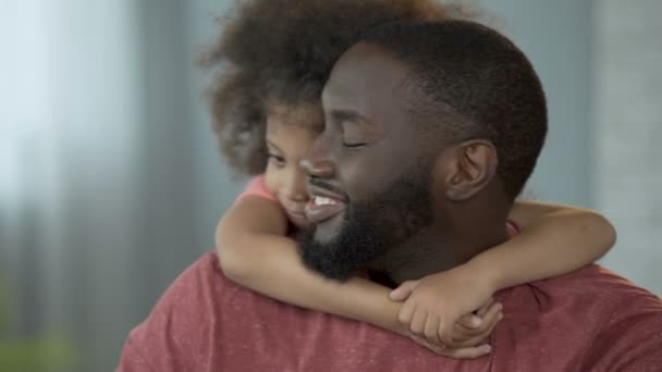 Linda chica abrazando a su padre alrededor del cuello firmemente con sus pequeñas manos, ternura — Vídeos de Stock