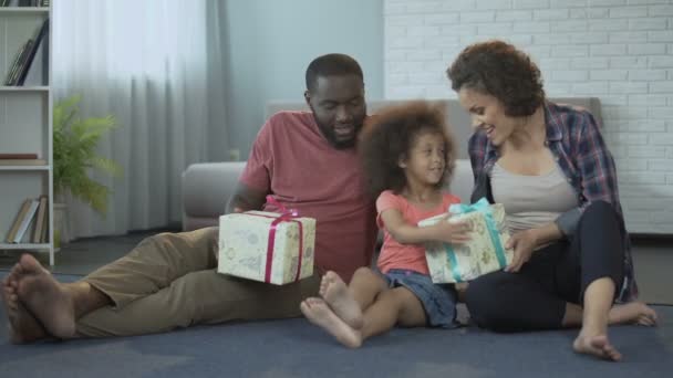 Linda niña recibiendo regalos de los padres para su cumpleaños en la sala de estar — Vídeo de stock