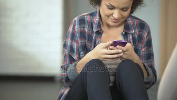 Усміхнена молода жінка спілкується з друзями по телефону, додатки соціальних мереж — стокове відео