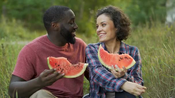 Schwarz-weißes Paar amüsiert sich und isst köstliche Wassermelone — Stockvideo