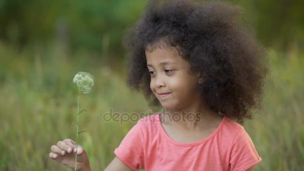 Little lonesome kid standing in garden and playing with small white flower — Stock Video