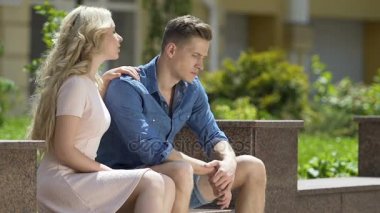 Bankta oturan ve kıskanç erkek arkadaşı, kızgınlık sarılma sarışın kız