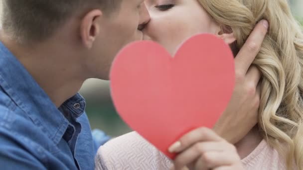 Detail o vášnivý polibek milující lidé, muž a žena držící papírové srdce