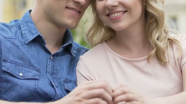 Closeup of smiling couple making heart symbol with hands outdoors, love — Stock Video