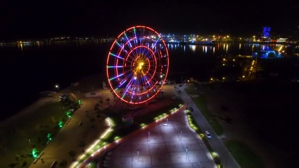 Ferris wheel sparking with lights, Batumi nightscape reflecting in Black sea — Stock Video