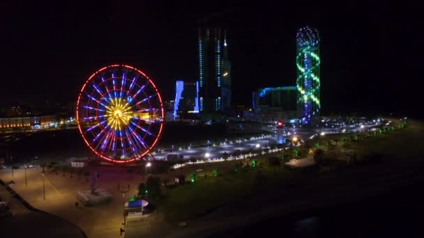 Потрясающий вид на панорамное колесо и алфавитную подсветку башни ночью — стоковое видео