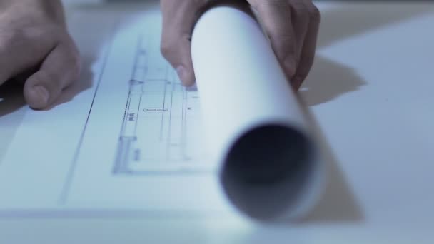 Inženýr rozvinutí výkres budovy na tabulce u úřadu, slow-mo