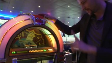 Neşeli adam şarkı vintage müzik kutusunu seçerek eğlenceli bar, parti