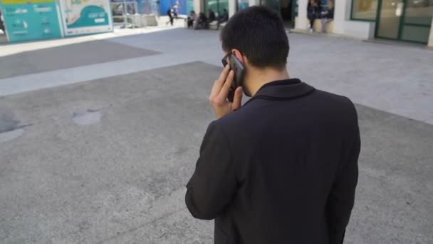 Busy man in dark suit speaking over phone and walking city street, active life — Stock Video