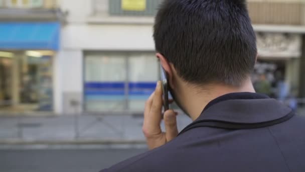 Rückansicht eines großen Mannes, der emotional am Telefon in der Stadtstraße diskutiert — Stockvideo