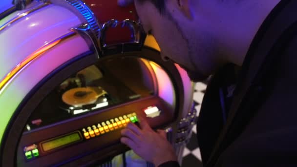 Man försöker välja bra låt på gamla jukebox släppa myntet och trycka tangenter — Stockvideo