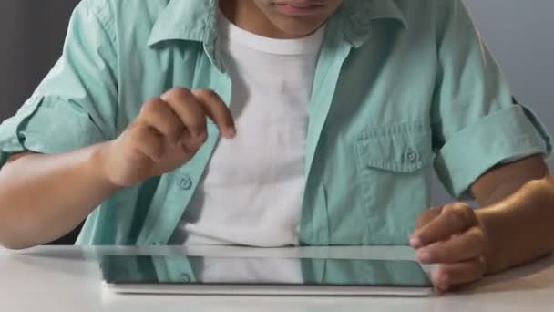 Мужчина смешанной расы прокручивает экран планшета за столом, смотрит онлайн мультфильмы — стоковое видео