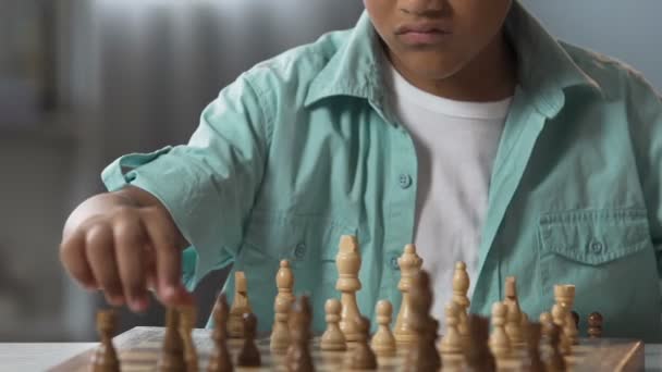 Petit enfant dans des lunettes assis à table et jouant aux échecs, classe d'école, passe-temps — Video