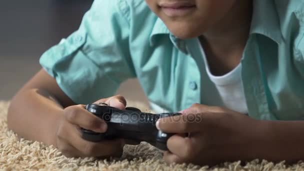 Μικρό παιδί ξαπλωμένο στο πάτωμα με παιχνίδι σταθμό ελέγχου παίζοντας βιντεοπαιχνίδια, θυμό — Αρχείο Βίντεο