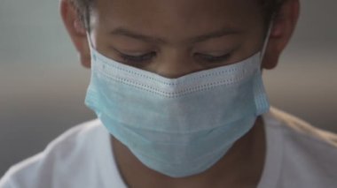 Kameraya bakarak öfkeyle, yüz maskesi biracial çocuk sağlık Dispanseri