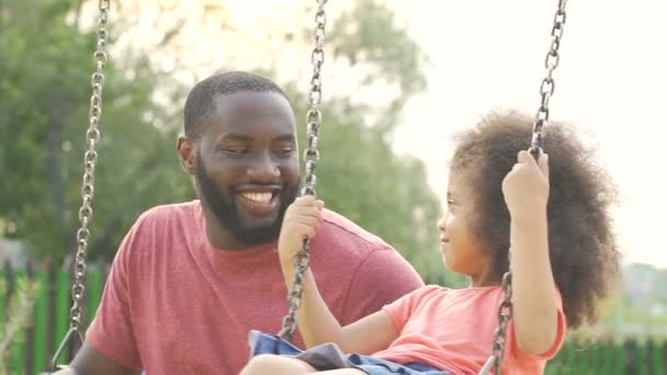 Cuidar al padre afroamericano balanceando a su pequeña hija, feliz fin de semana familiar — Vídeos de Stock