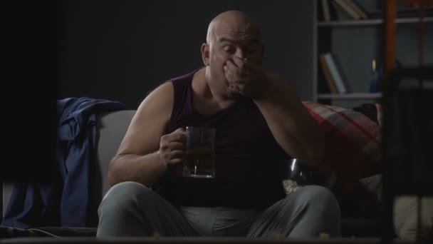 Plump guy watching TV with popcorn and beer, unemployment and laziness problems — Stock Video