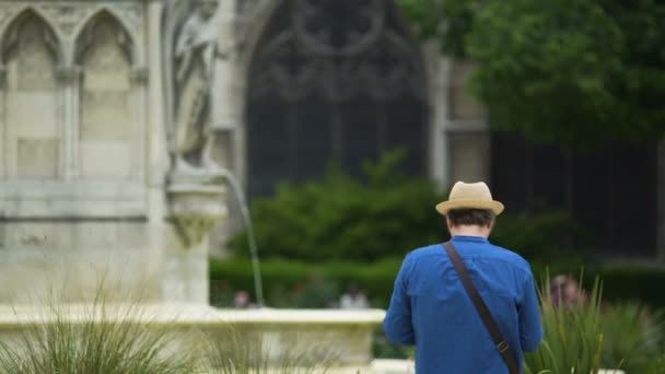 Hombre fotografiando la antigua fuente de la Virgen y Notre Dame de Paris — Vídeos de Stock