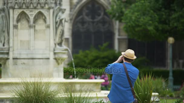 Intresserad av manliga turist tar ett foto av fontänen och Notre-Dame de Paris — Stockvideo