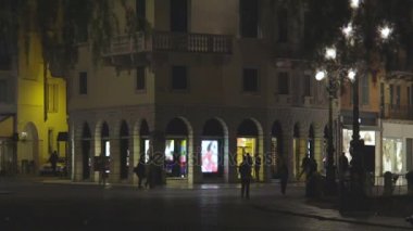 Birkaç kişi tarafından modern binasında gece caddede birçok kemerli yürüyüş