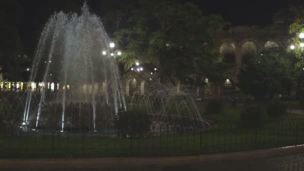 Зажег струи воды, стреляя в воздух, парк фонтан ночью, уличные фонари вокруг — стоковое видео