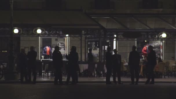 Siluetas de personas hablando frente a restaurante vacío con mesas afuera — Vídeos de Stock