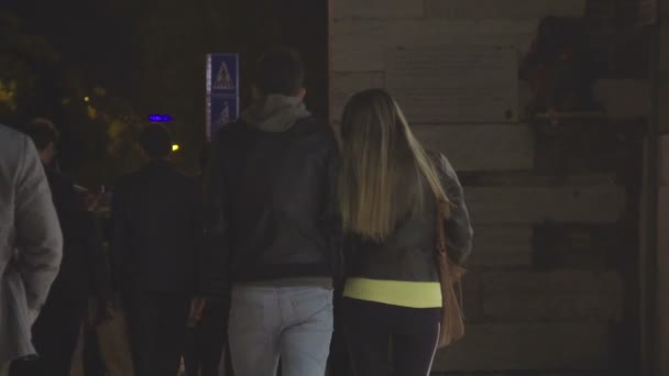 Casal jovem andando na multidão rua abaixo à noite, vida noturna da cidade, câmera lenta — Vídeo de Stock