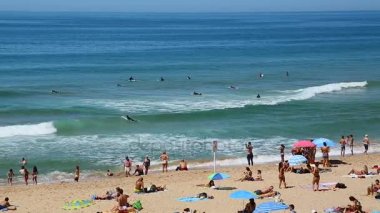 Cascais, Portekiz - yaklaşık Ağustos 2014: İnsanlar sahilde. Plaj üzerine güneşlenme, okyanusta yüzmeye sörfçü insanlarla inişli çıkışlı dalgalar dinlenme