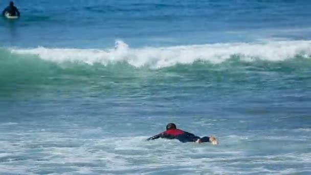 Чоловіки намагаючись плавати на борту серфінг через хвилі в океані, літній активний спорт — стокове відео