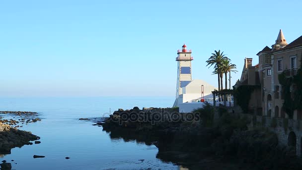 Canal de agua estrecho con la calma del mar detrás y la casa de luz de pie en la costa — Vídeos de Stock