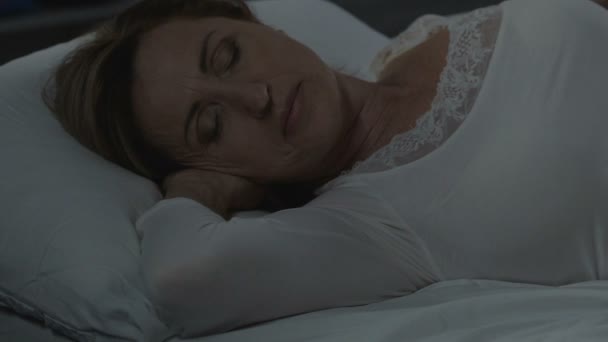 Женщина мирно лежит на удобной кровати, здоровый сон, ортопедический матрас — стоковое видео