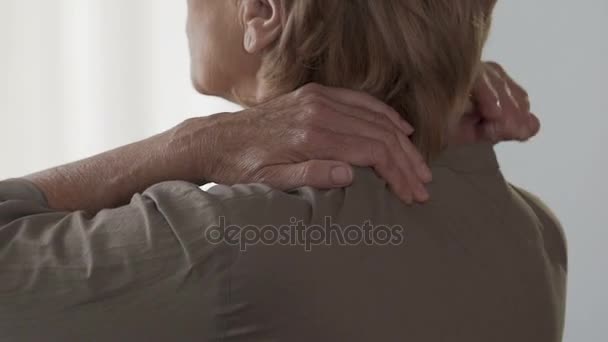 Пожилая женщина массирует шею и плечи, чувствует боль и дискомфорт — стоковое видео