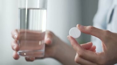 Bardak su tutan kadın tablet aspirin koyarak ağrı kesici