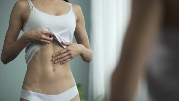 Nespokojená žena stojící před zrcadlem, při pohledu na její štíhlé tělo, dieta — Stock video