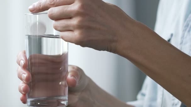 Kobieta trzyma szklankę wody, wprowadzanie tabletki aspiryny do niego zwolnionym tempie — Wideo stockowe