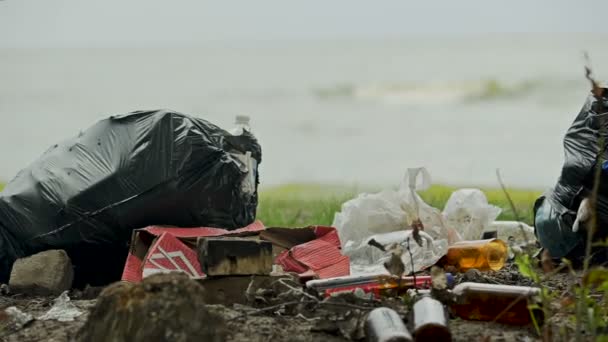 Saçma sapan şeyler kıyısında, çevresel tehlikeleri ihmal insanlar büyük plastik torbalar — Stok video